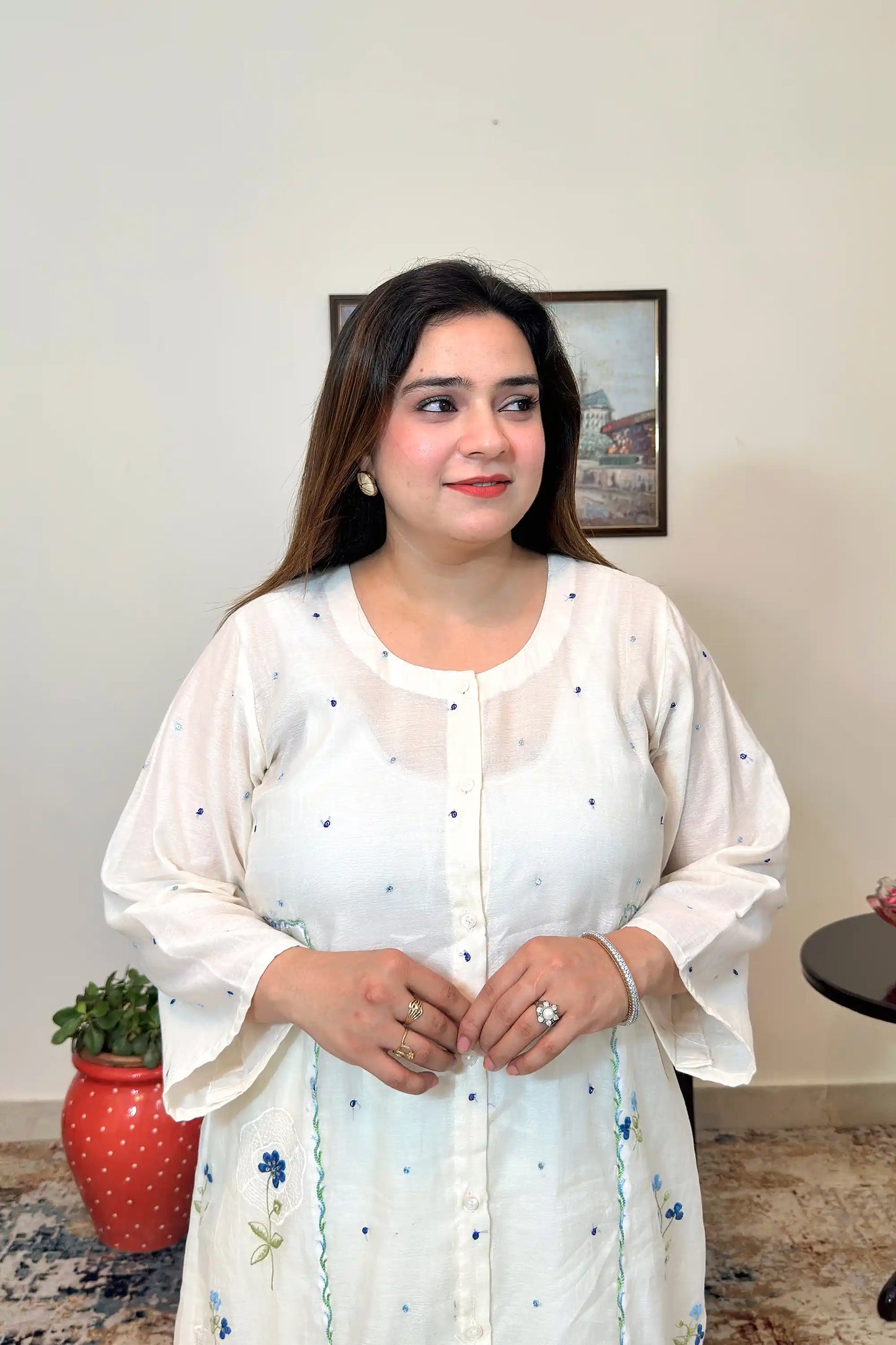Front view close-up of an off-white chanderi kurta showing the button placket and scattered blue floral resham embroidery.