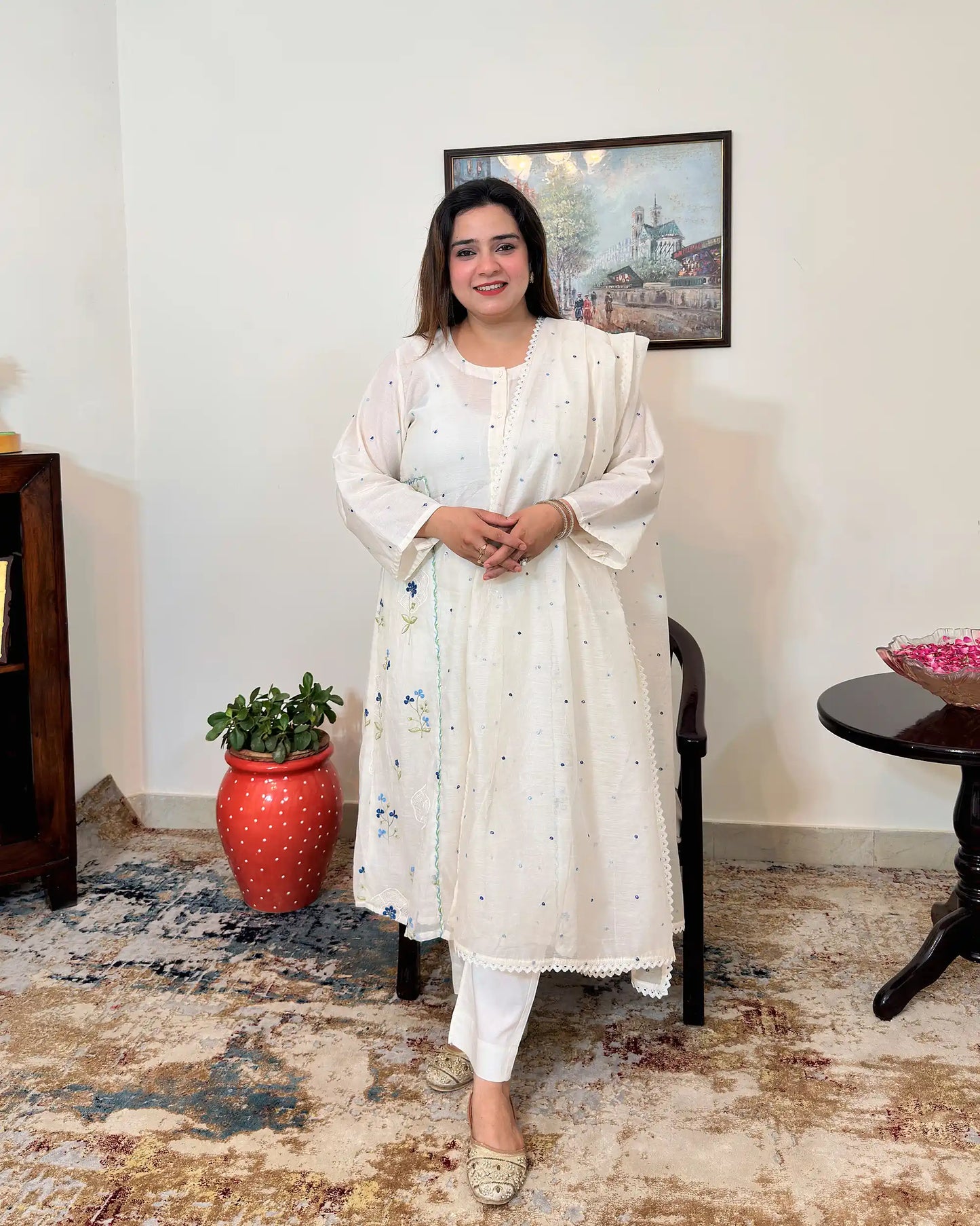 Front view of an off-white chanderi A-line kurta with dupatta on, showing blue floral resham embroidery on the kurta and scattered floral resham embroidery with a lace edge on the dupatta, paired with off-white trousers.