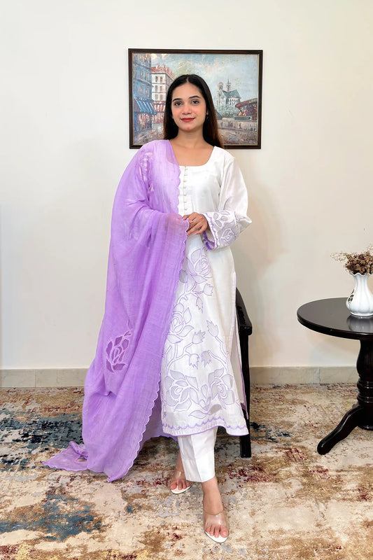 Front view of a woman wearing an off-white chanderi straight kurta with floral cutwork embroidery on the sleeves and hem, paired with a purple chanderi dupatta with floral cutwork and off-white trousers, dupatta on.