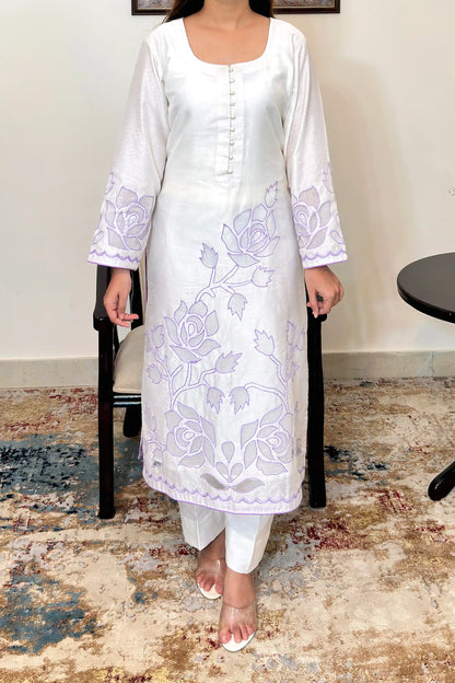 Front view of the off-white chanderi straight kurta with floral cutwork embroidery on the sleeves and hem, paired with off-white trousers.