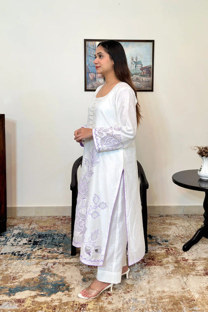 Side view of the off-white chanderi straight kurta with floral cutwork embroidery on the sleeves and hem, paired with off-white trousers.