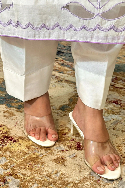 Close-up of the hem of the off-white chanderi kurta with floral cutwork embroidery, worn over off-white trousers.