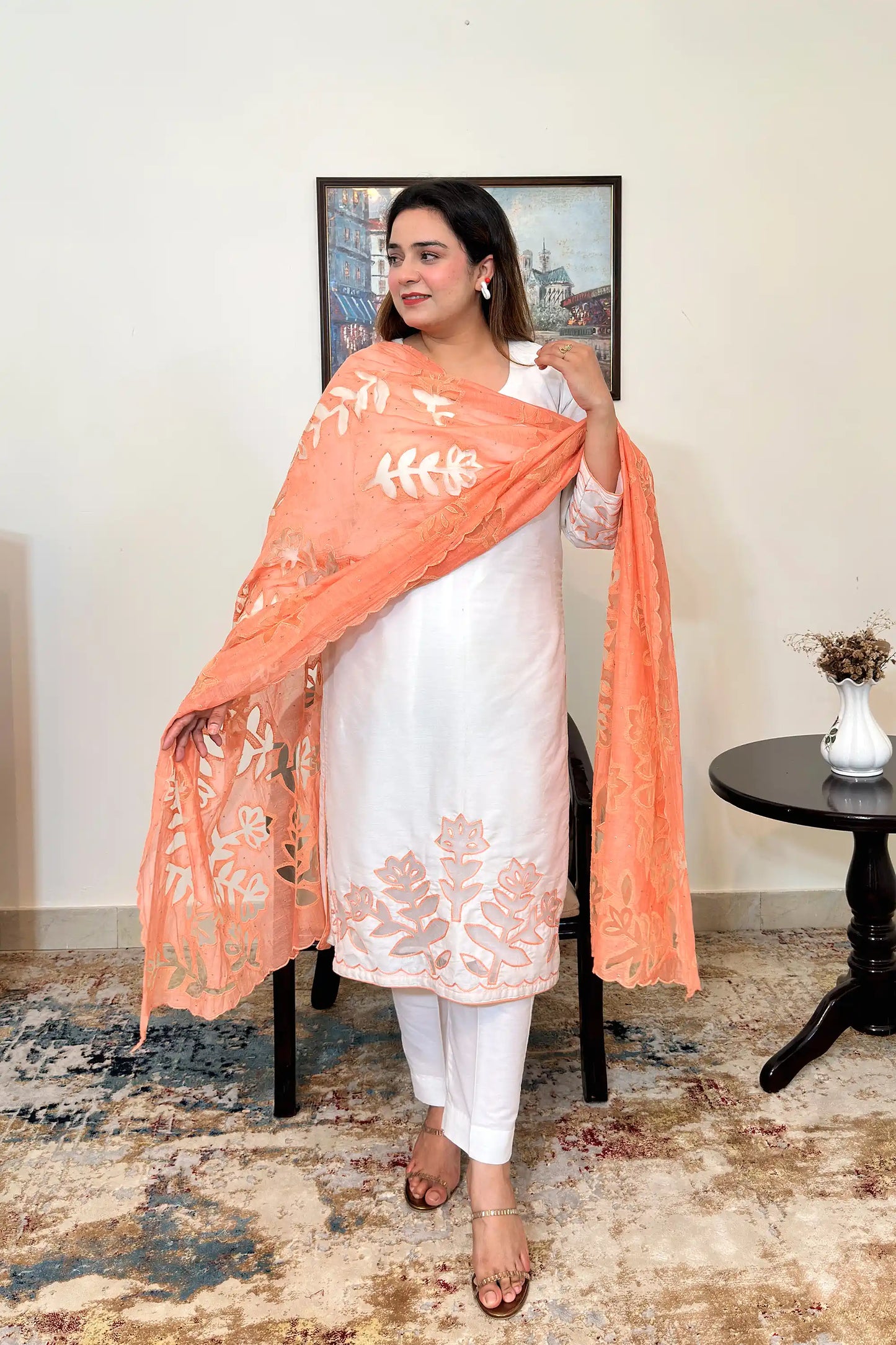 Front view of an off-white chanderi straight kurta with floral cutwork on the sleeves and hem, worn with a peach dupatta featuring floral cutwork, dupatta on, and off-white trousers.
