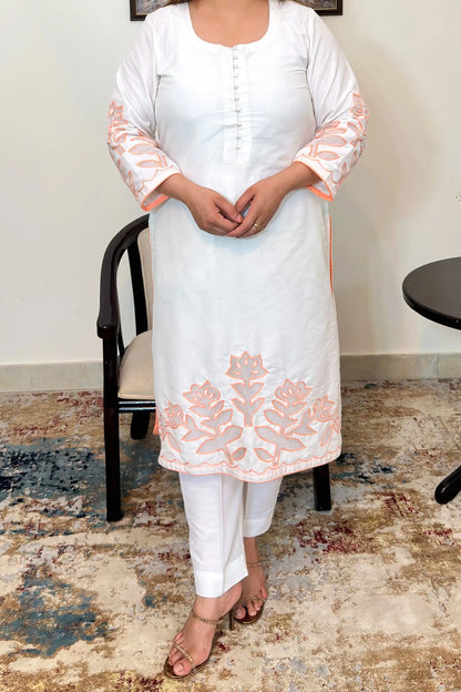 Close-up front view of the off-white chanderi straight kurta showing the button placket and floral cutwork on the sleeve and hem, with off-white trousers.