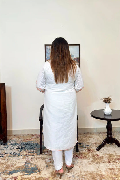 Back view of the off-white chanderi straight kurta with floral cutwork on the sleeves, worn with off-white trousers.