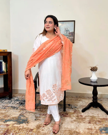 Front view of the off-white chanderi straight kurta with floral cutwork on the sleeve and hem, worn with a peach dupatta featuring floral cutwork, and off-white trousers.
