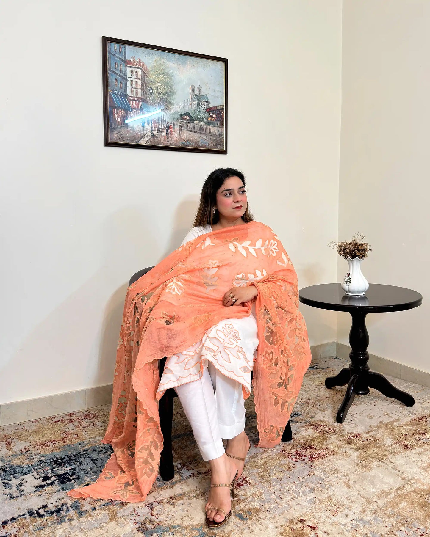 Front view of the off-white chanderi straight kurta with floral cutwork on the hem, worn with a peach dupatta featuring floral cutwork, and off-white trousers.
