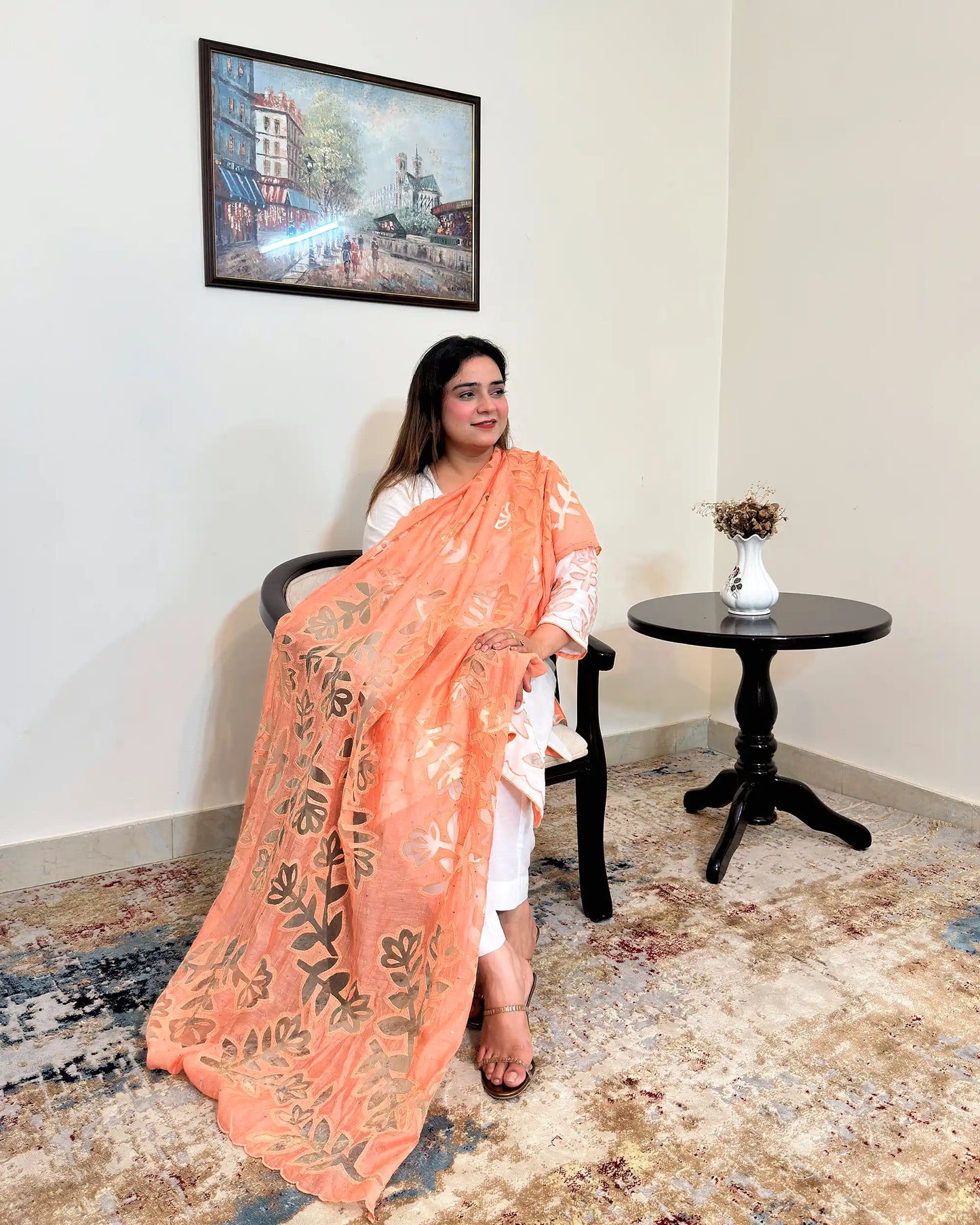 Front view of the off-white chanderi straight kurta with floral cutwork on the sleeve, worn with a peach dupatta featuring floral cutwork, and off-white trousers.