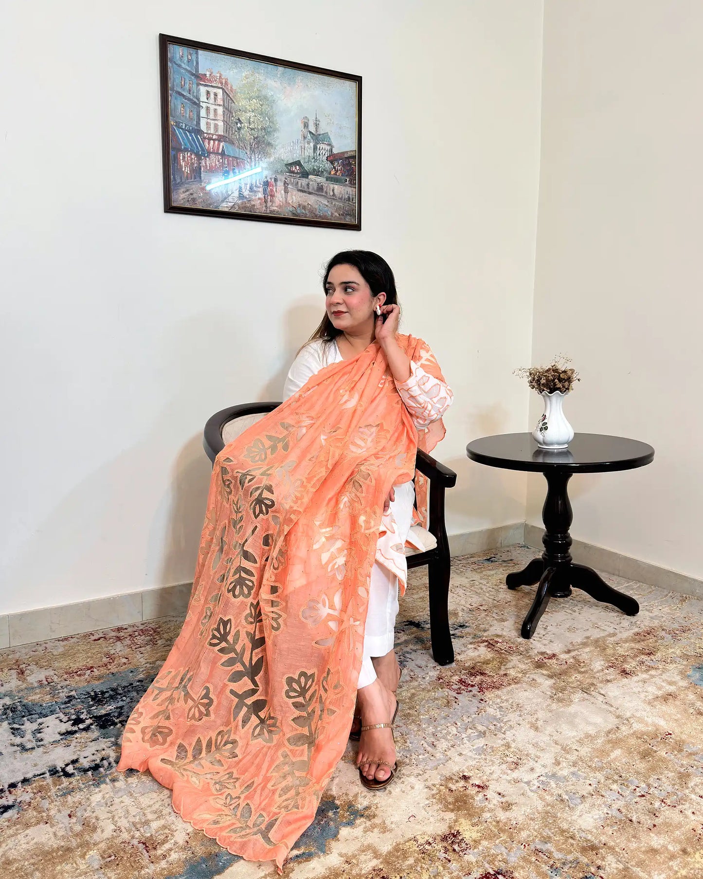 Front view of the off-white chanderi straight kurta with floral cutwork on the sleeve, worn with a peach dupatta featuring floral cutwork, and off-white trousers.