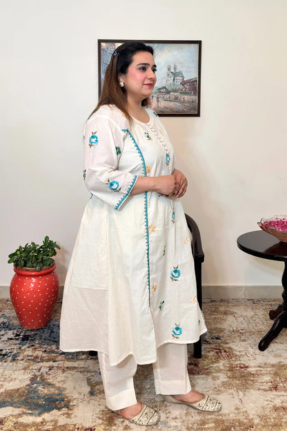 Side view of an off-white cotton frock kurta with multicolour floral resham embroidery, worn with off-white trousers.