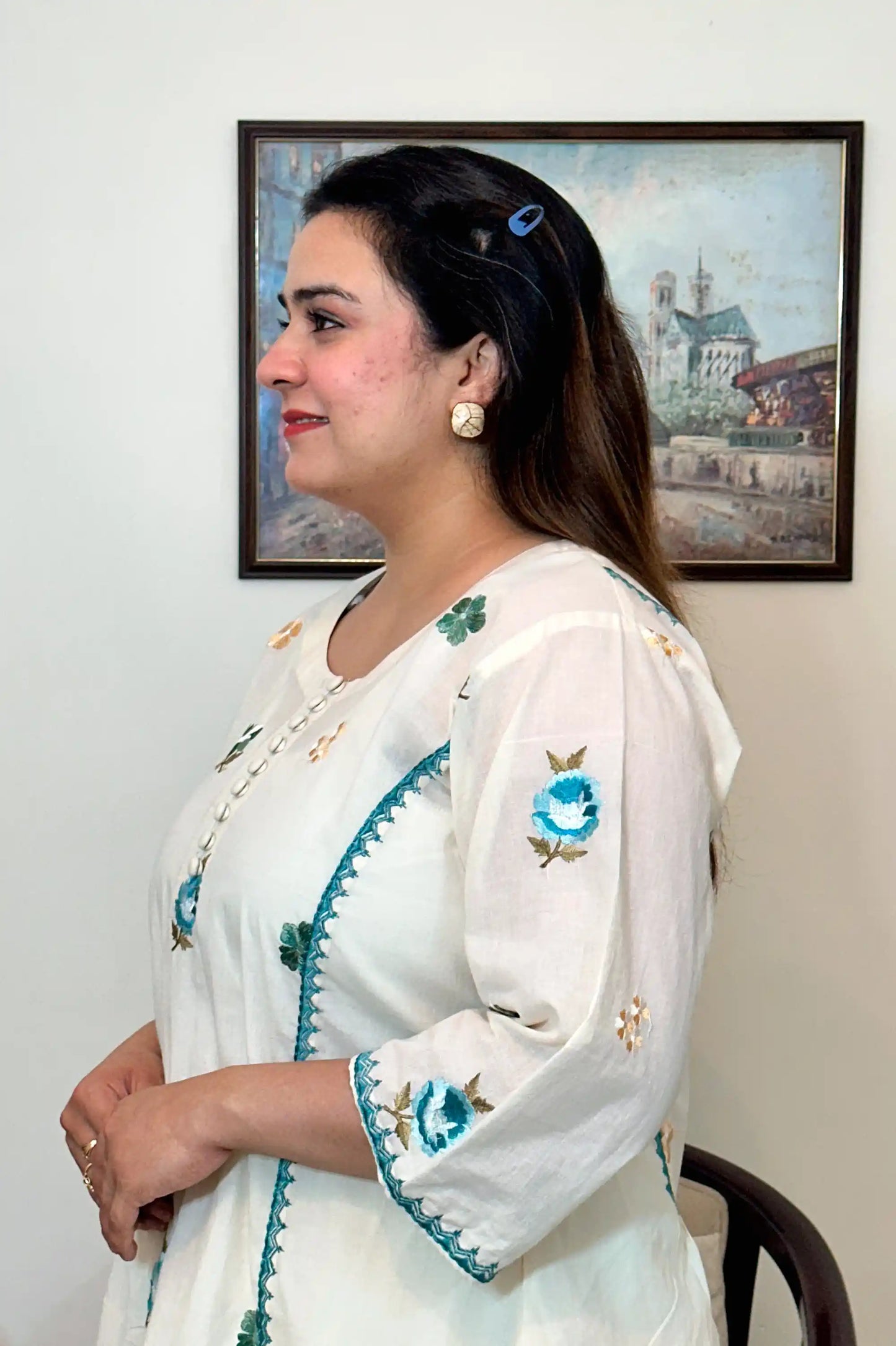 Close-up side view of an off-white cotton frock kurta showing multicolour floral resham embroidery along the button placket and sleeve.