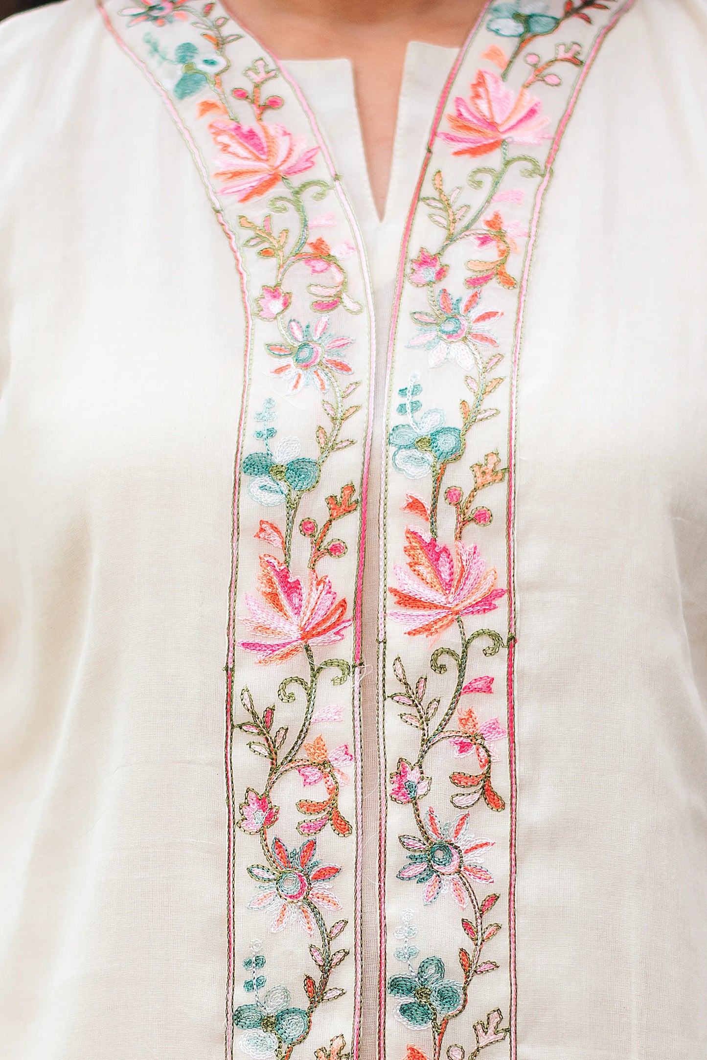 Close-up of intricate Kashmiri embroidery on the chest of an off-white tunic