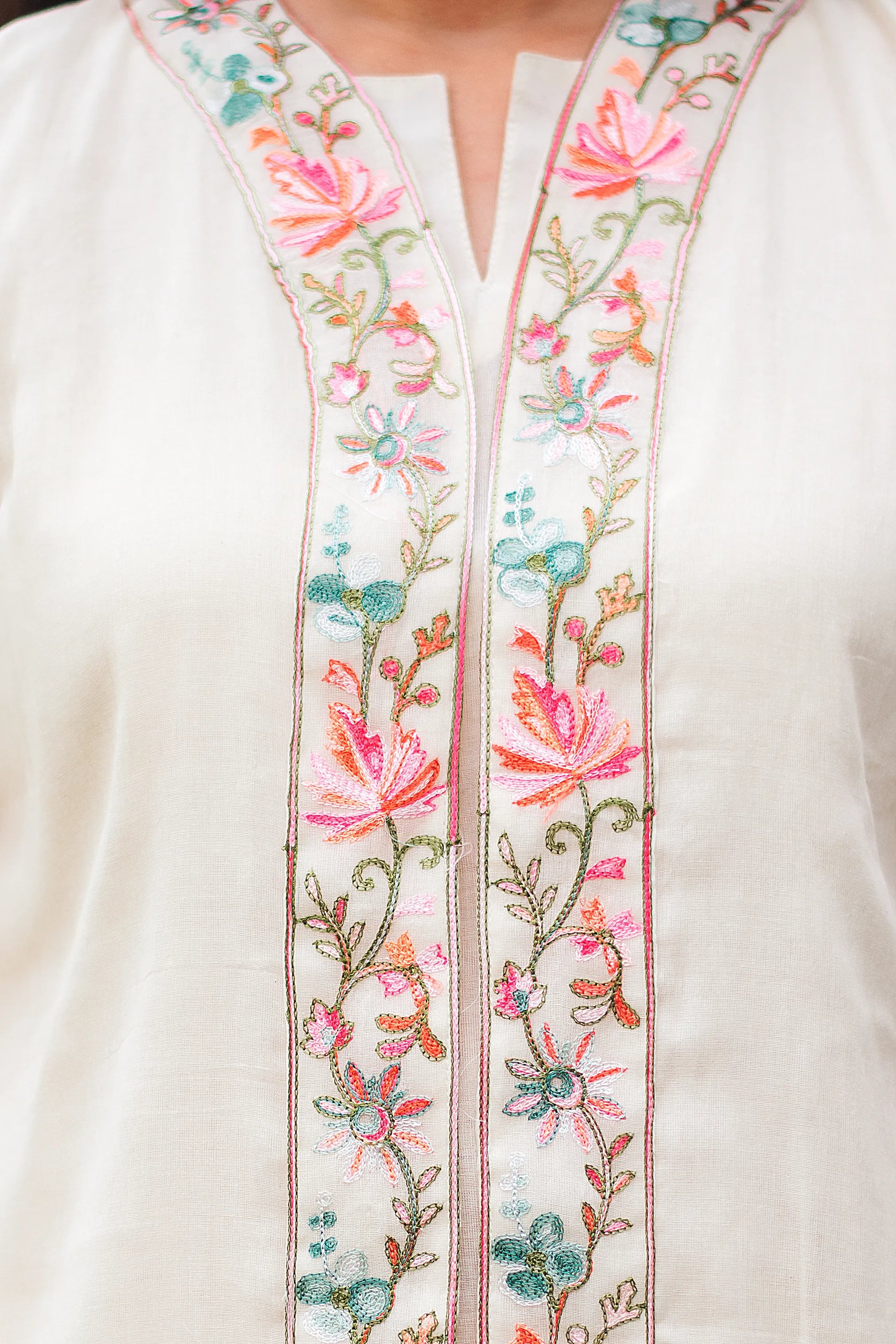 Close-up of intricate Kashmiri embroidery on the chest of an off-white tunic