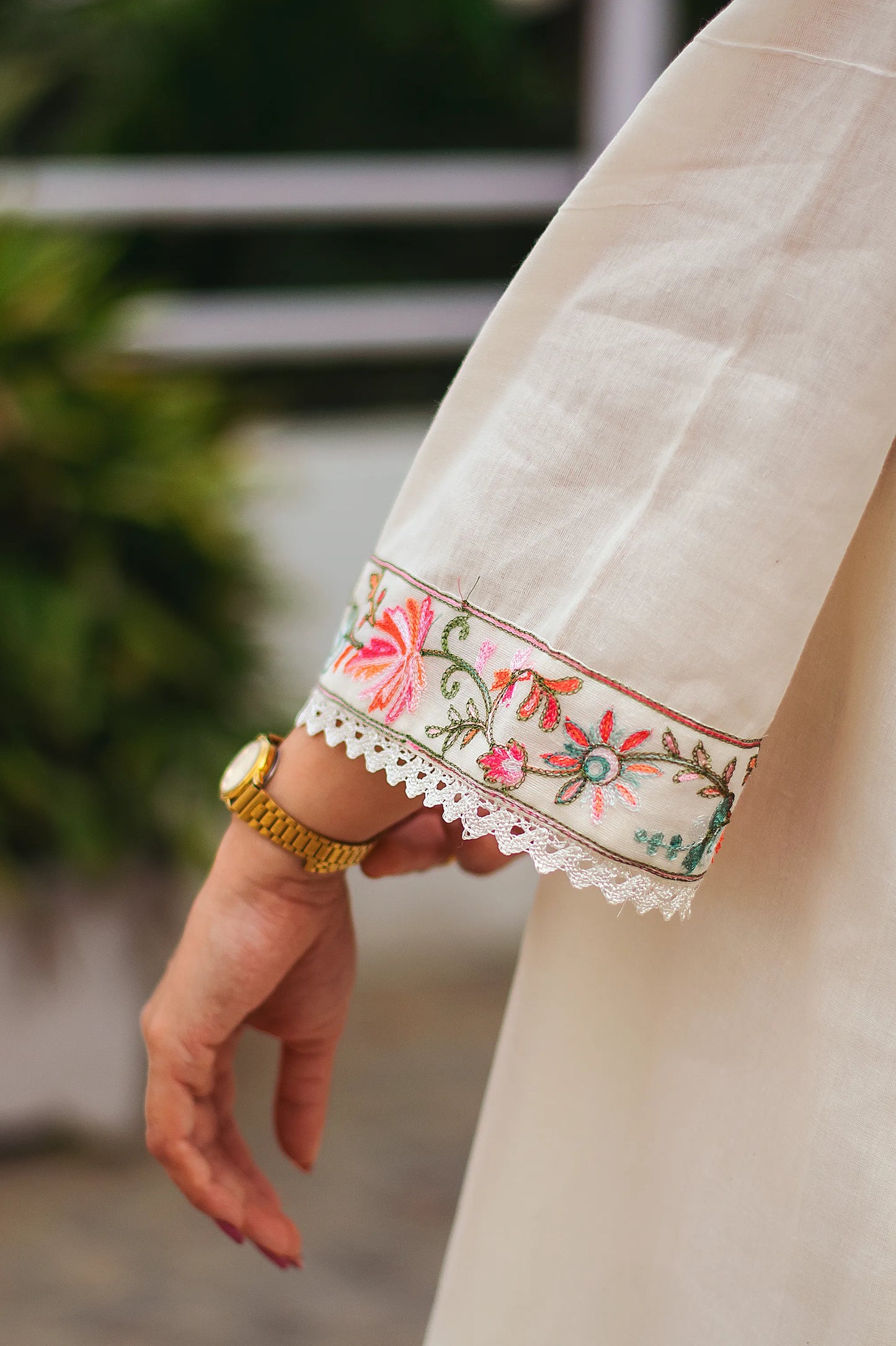 An Indian woman wearing an off-white asymmetric kurta set, her hand gently resting on her side