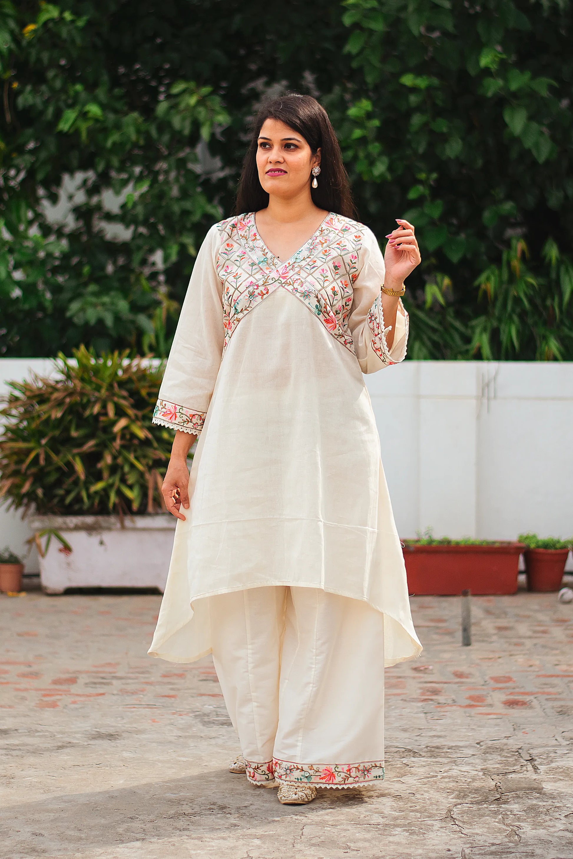 An Indian woman modeling a stunning off-white asymmetric kurta set