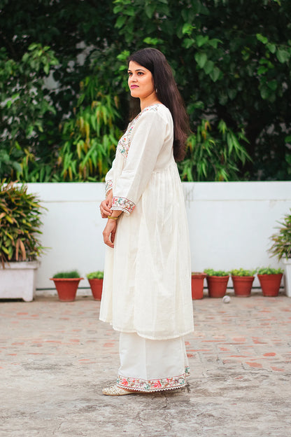 Side view of Indian model in an off-white cotton Anarkali kurta with Kashmiri embroidery, paired with matching off-white palazzo