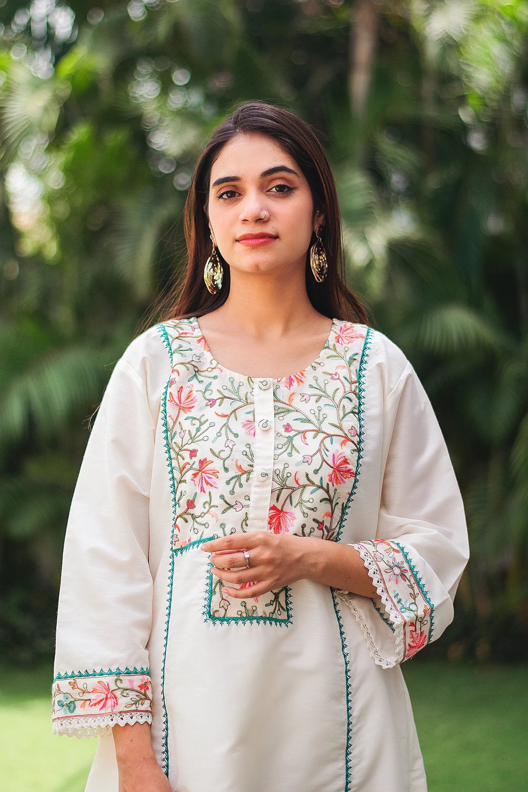 Close-up of the model focusing on the Kashmiri floral embroidery on the yoke of the off-white cotton kurta.