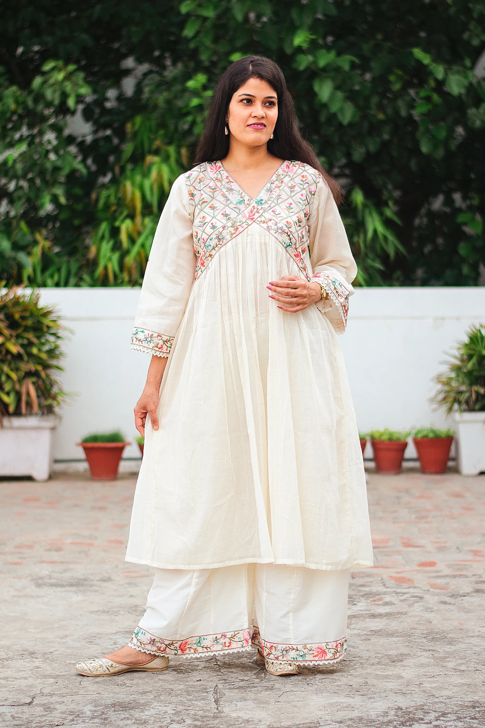 Indian model dressed in an off-white cotton Anarkali kurta with floral Kashmiri embroidery, matched with off-white palazzo