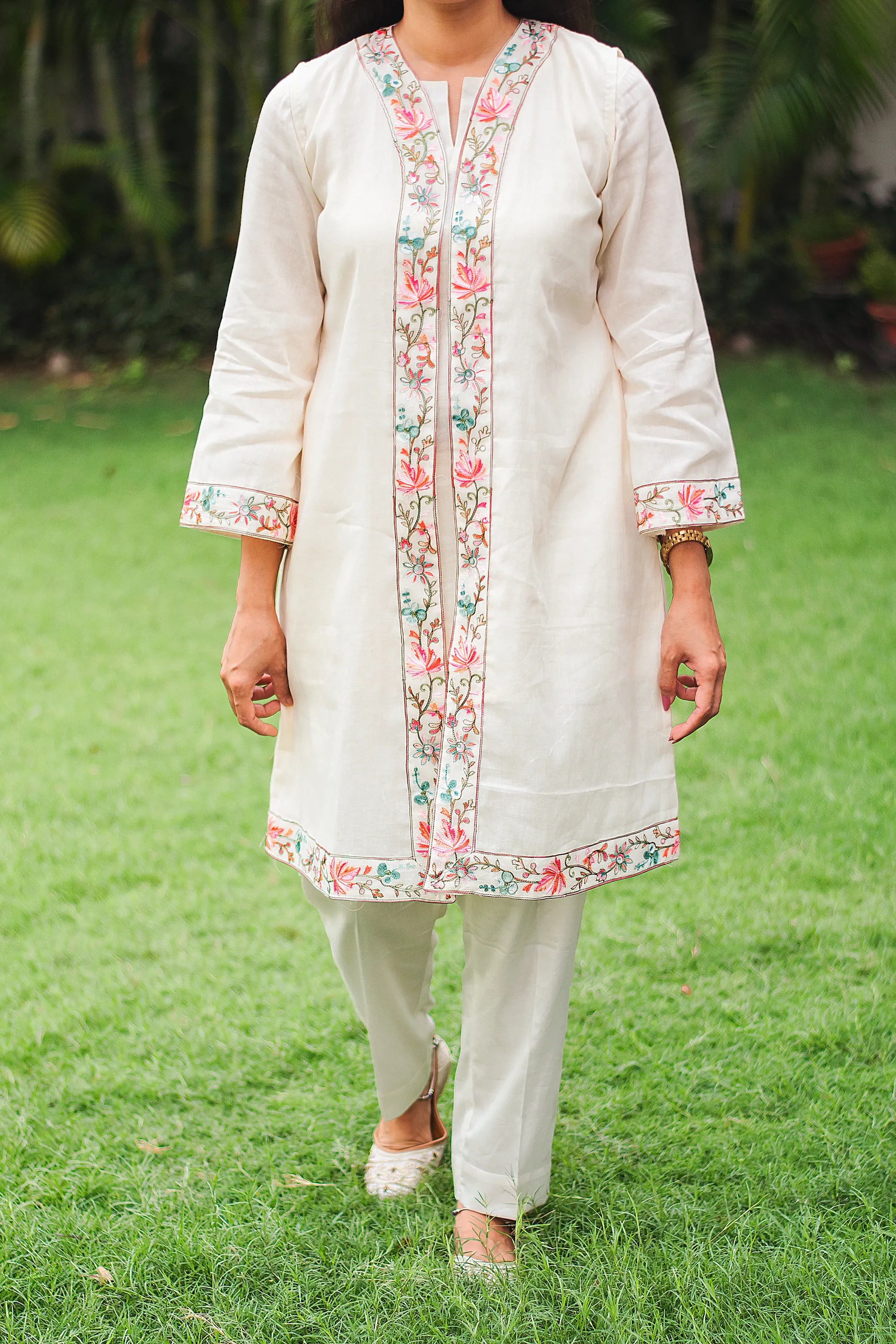 Close-up of intricate Kashmiri embroidery on an off-white tunic and trousers