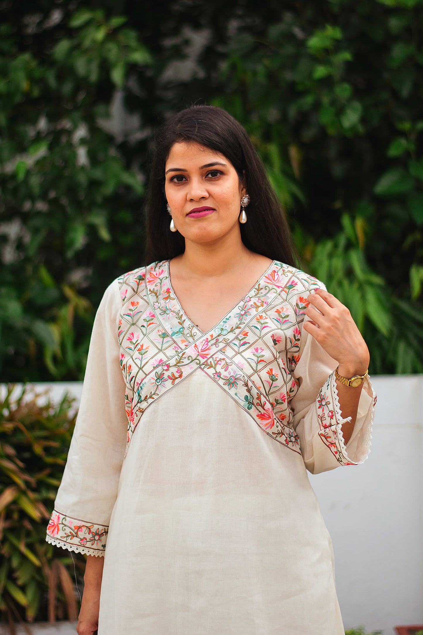 An Indian woman facing forward wearing an off-white asymmetric kurta set