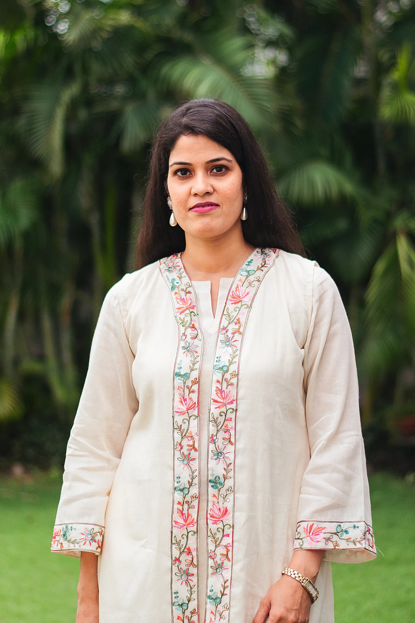 Indian model wearing an off-white tunic and trousers set, highlighting the intricate Kashmiri embroidery details with a close-up of her face