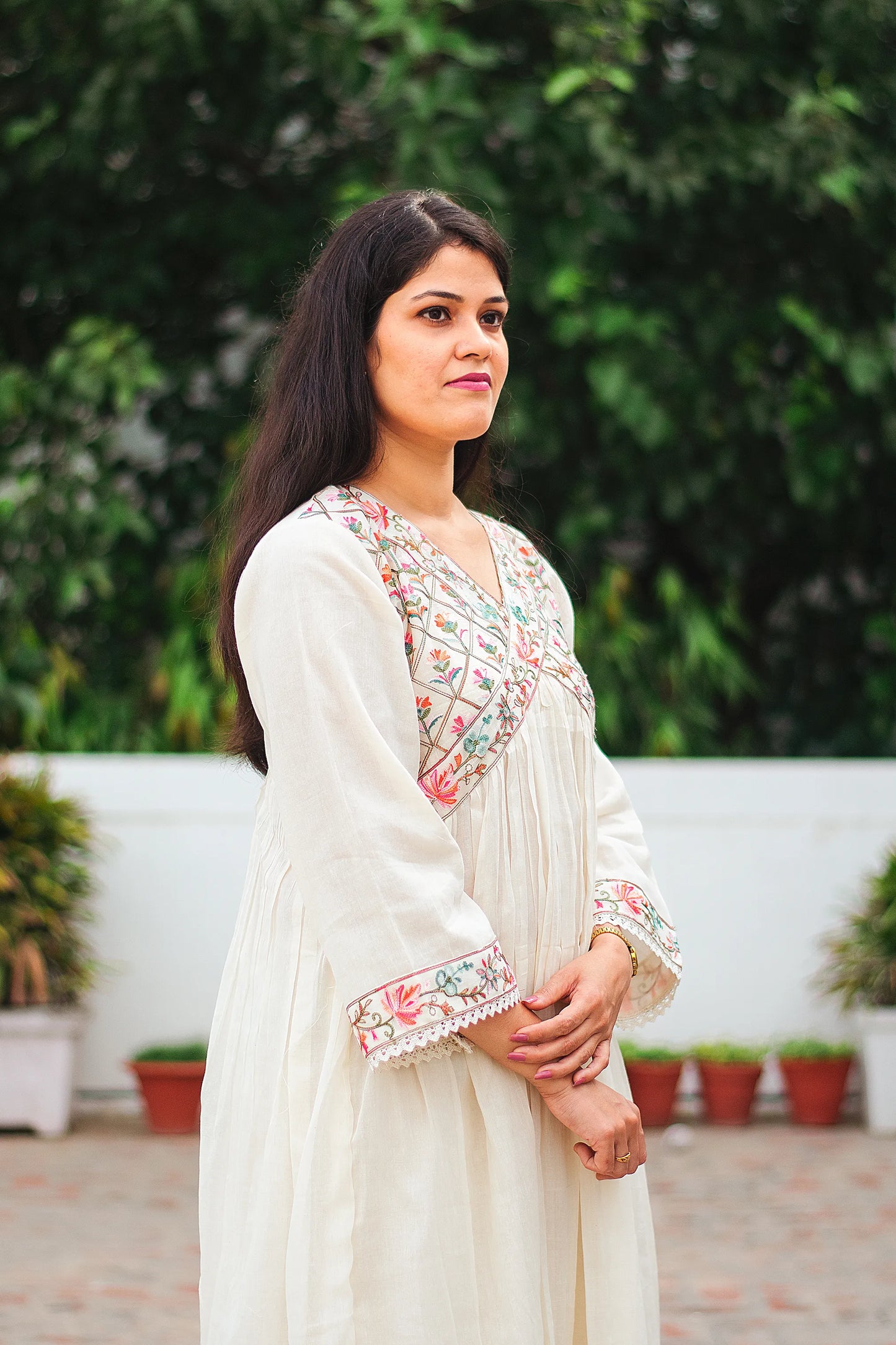 Side view of Indian model in an off-white cotton Anarkali kurta with Kashmiri embroidery.