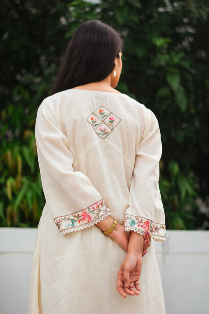 An Indian woman facing away, wearing an off-white asymmetric kurta set