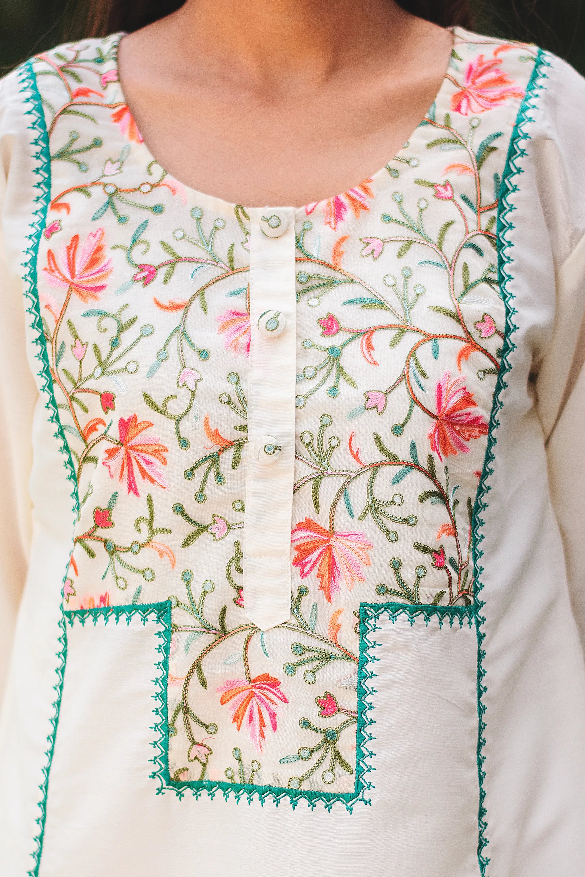 Close-up of Kashmiri floral embroidery on the yoke of an off-white cotton kurta.