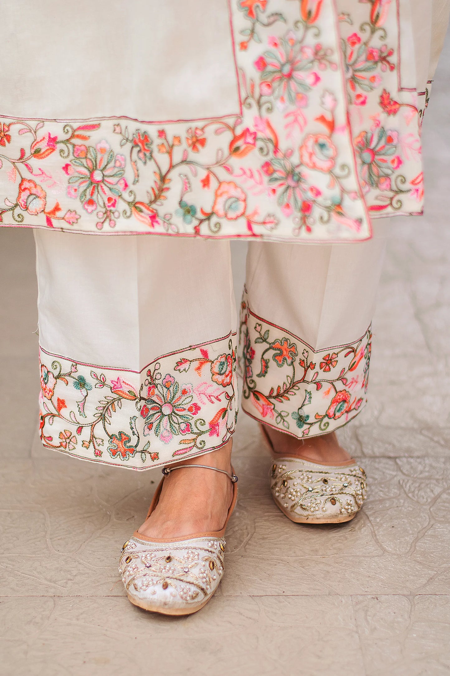 Close-up of off-white cotton trousers worn by the Indian model, highlighting the Kashmiri work at the hem.