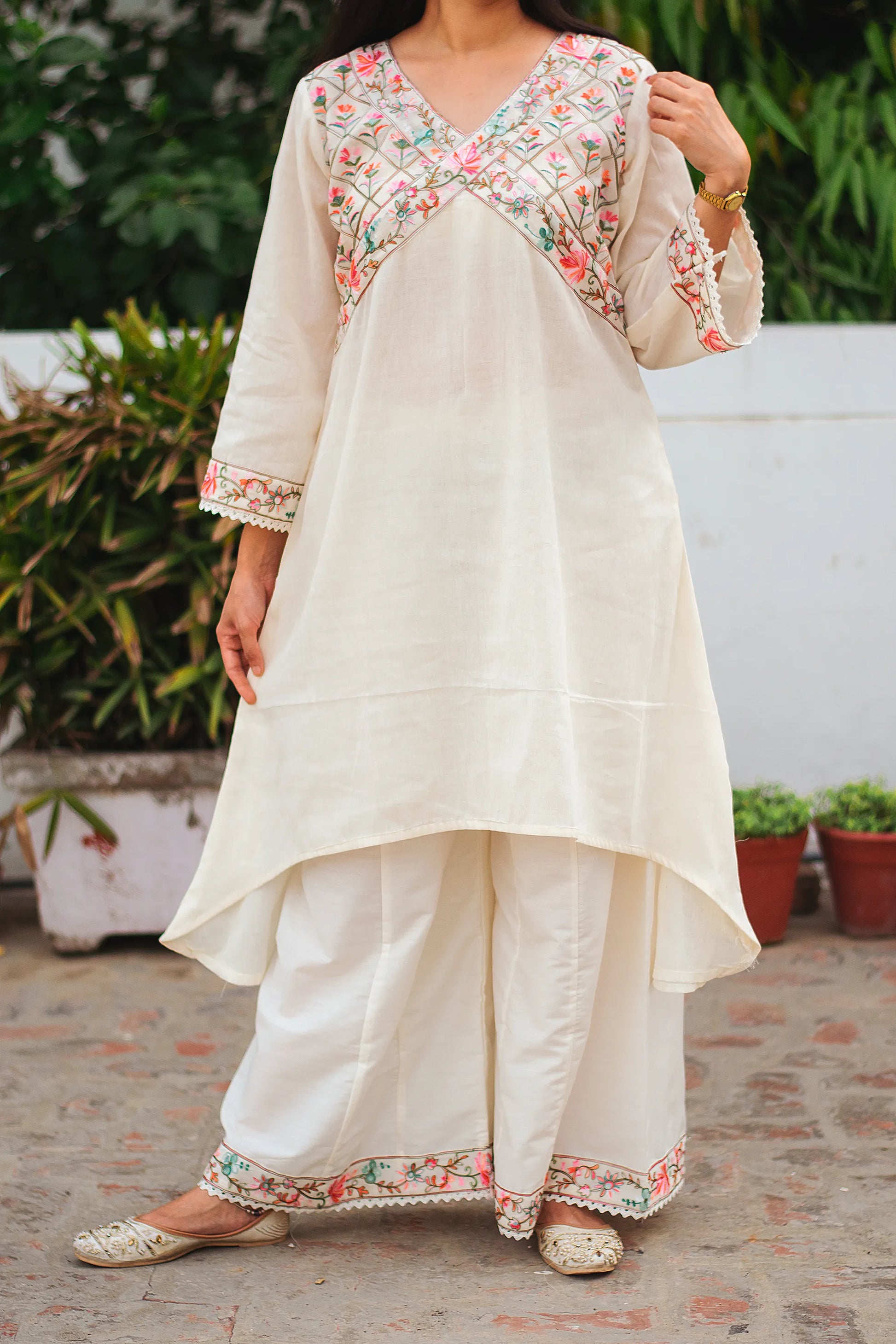 An Indian woman wearing an off-white asymmetric kurta set