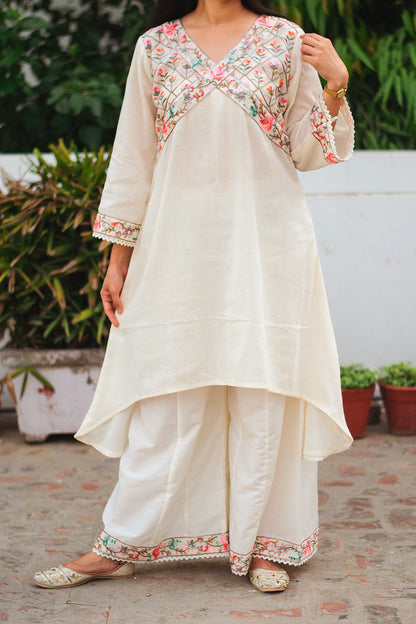 An Indian woman wearing an off-white asymmetric kurta set