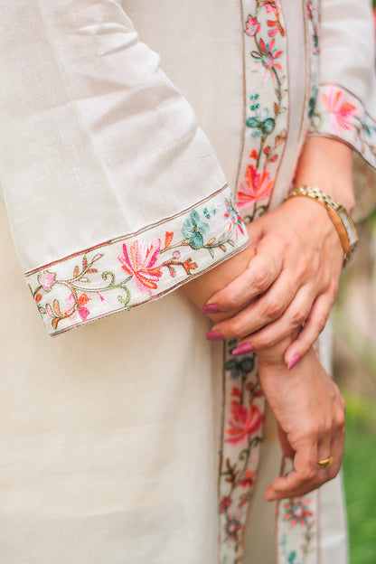 Close-up of hands holding a delicate, embroidered off-white dupatta with intricate Kashmiri detailing