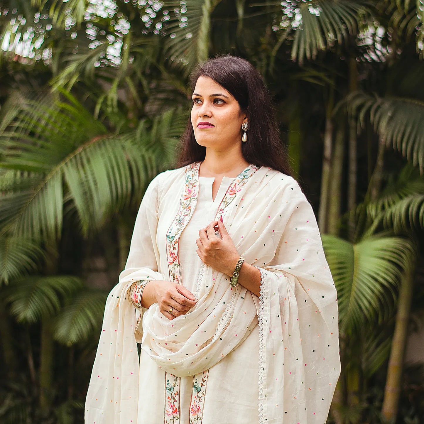 Indian model in a casual pose, wearing an off-white tunic and trousers set with delicate Kashmiri embroidery