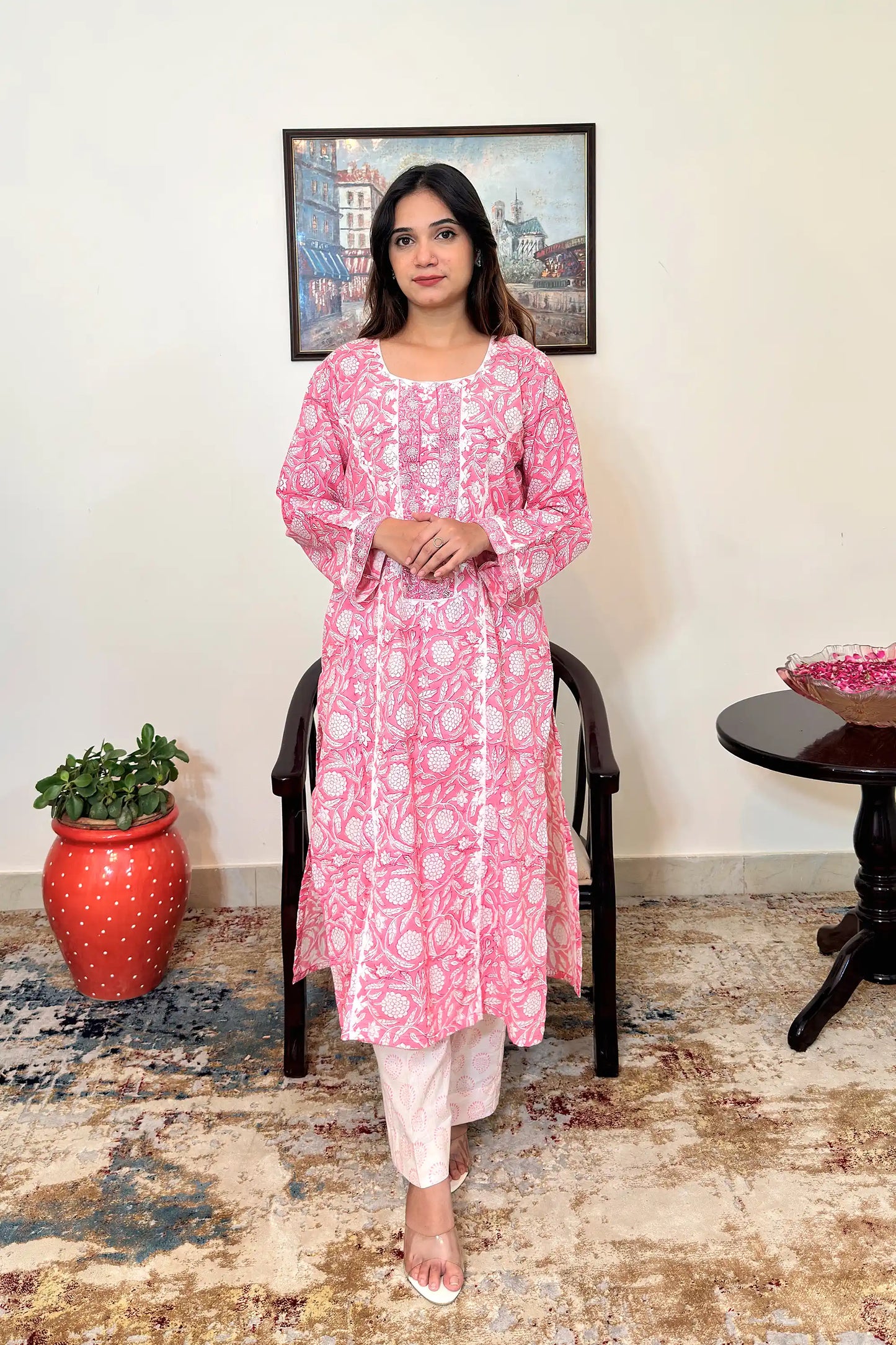 Front view of the pink floral block-printed mulmul cotton kalidar kurta and off-white printed trousers, showing the off-white appliqué yoke, appliqué work along the two front kalis, and the kurta's side slits.
