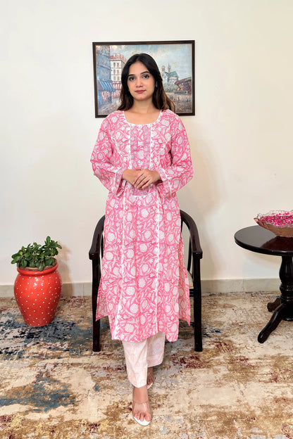 Front view of the pink floral block-printed mulmul cotton kalidar kurta and off-white printed trousers, showing the off-white appliqué yoke, appliqué work along the two front kalis, and the kurta's side slits.