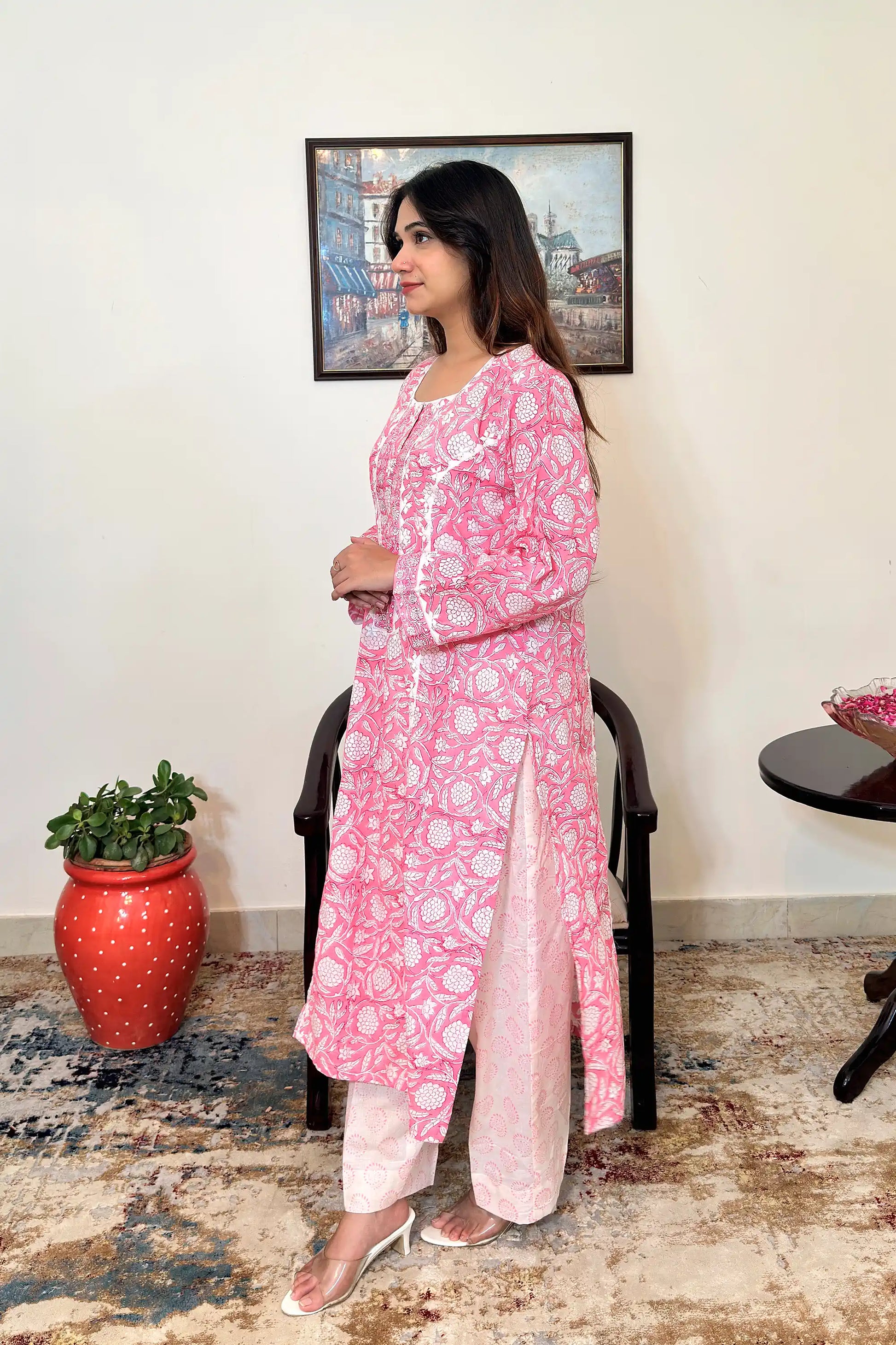 Left side view of the model wearing the pink floral block-printed mulmul cotton kalidar kurta and off-white printed trousers, showing the side slit and the off-white appliqué yoke.