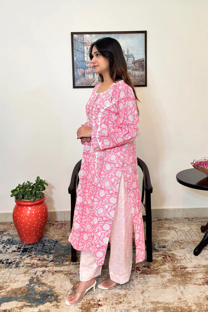 Left side view of the model wearing the pink floral block-printed mulmul cotton kalidar kurta and off-white printed trousers, showing the side slit and the off-white appliqué yoke.