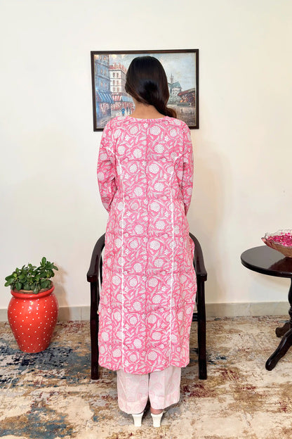 Back view of the model wearing the pink floral block-printed mulmul cotton kalidar kurta, showing appliqué work along the two back kalis and off-white printed trousers.