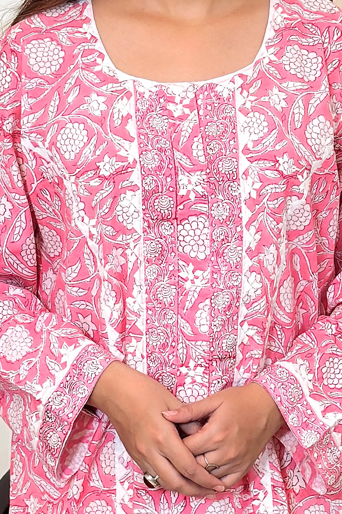 Close-up of the off-white appliqué yoke, showing the appliqué motifs and pink floral block print across the bodice.