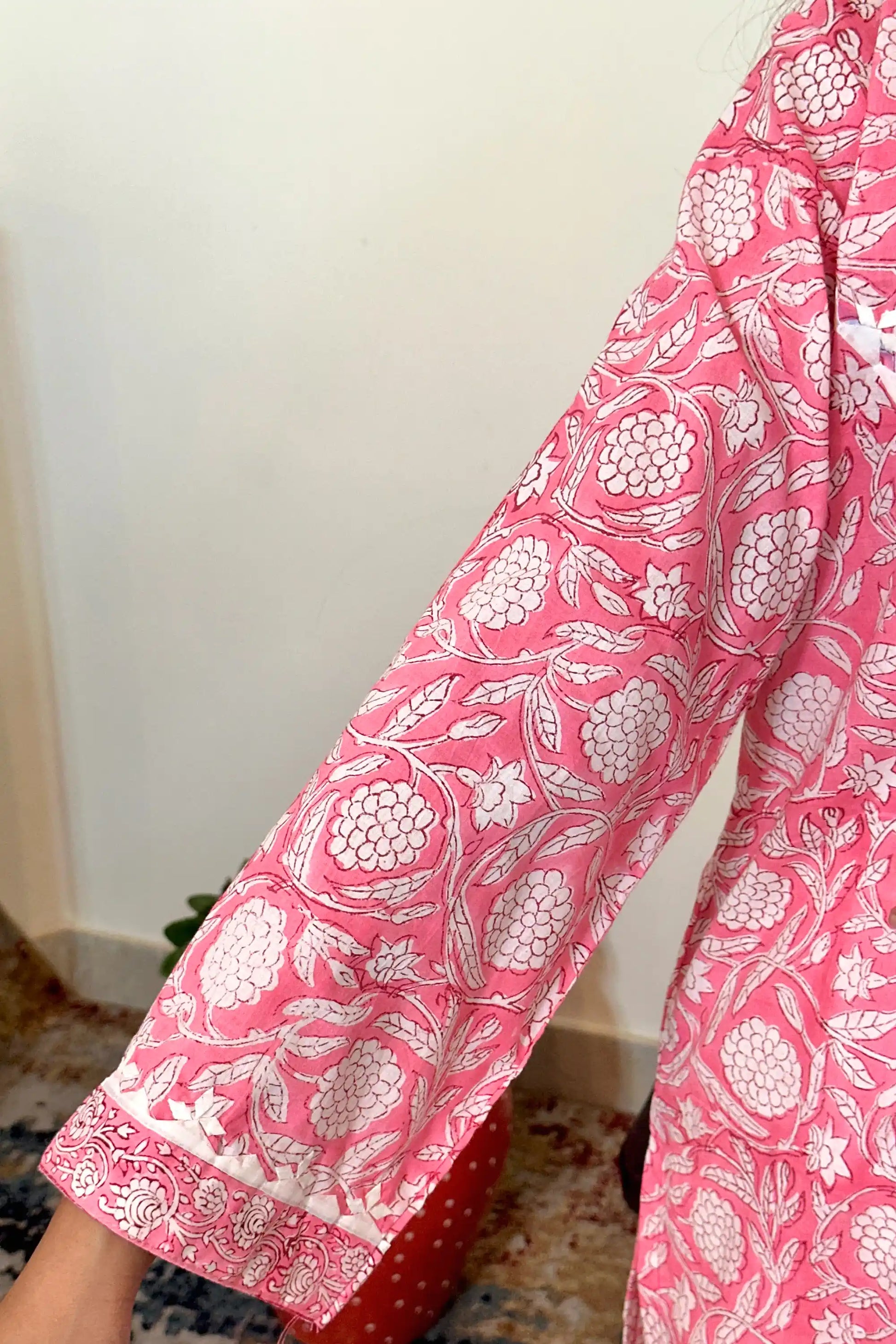 Close-up of the sleeve cuff, showing the pink floral block print and a printed paisley border along the hem.