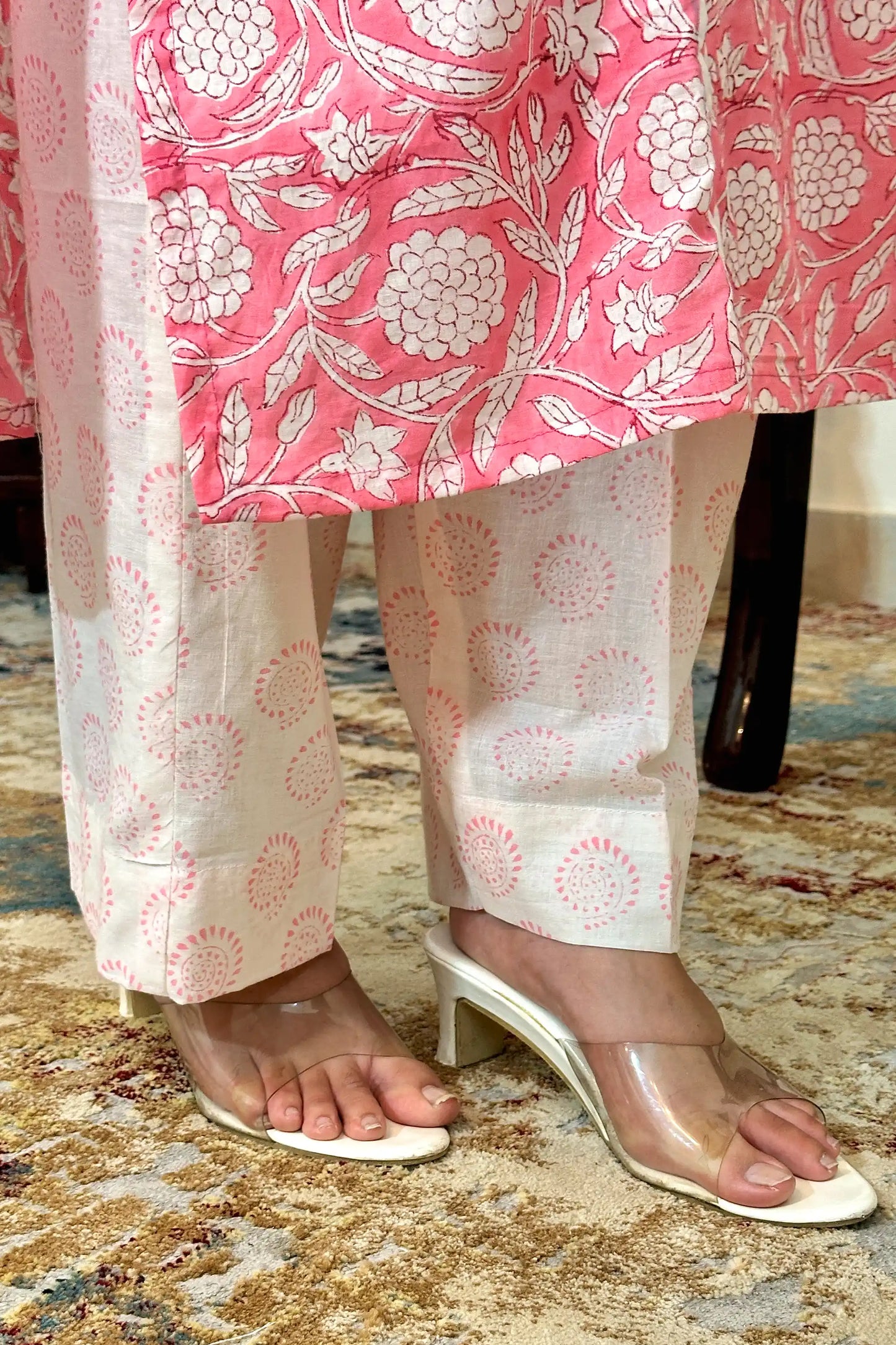 Close-up of the kurta hem meeting the off-white printed trousers, showing the pink floral block print along the kurta hem and circular block-print motifs on the trousers.