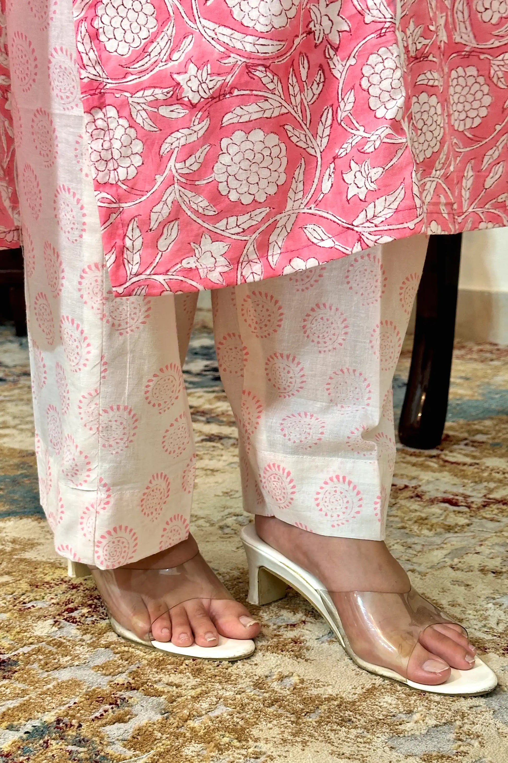 Close-up of the kurta hem meeting the off-white printed trousers, showing the pink floral block print along the kurta hem and circular block-print motifs on the trousers.