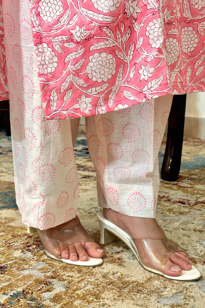 Close-up of the kurta hem meeting the off-white printed trousers, showing the pink floral block print along the kurta hem and circular block-print motifs on the trousers.