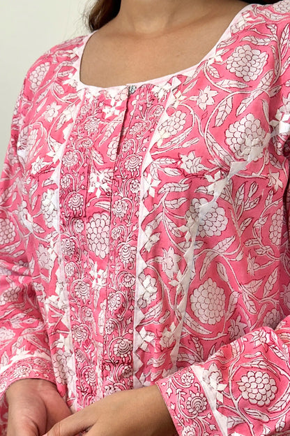 Close-up of the off-white appliqué yoke and neckline, showing the appliqué motifs, a metal hook-and-eye closure, and pink floral block print across the bodice.
