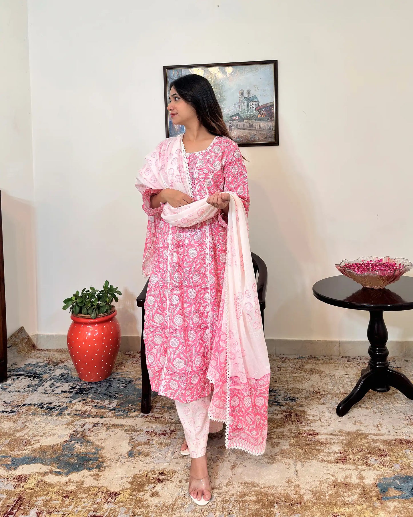 Model standing and holding the white mulmul dupatta with both hands, looking to the side, showing the dupatta's floral block print and lace-trimmed border along its length.