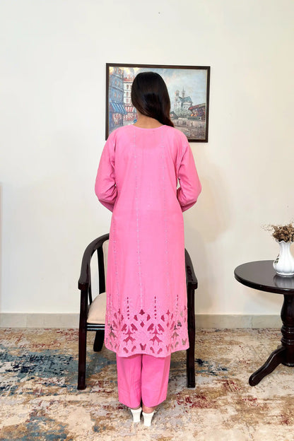Back view of the model wearing the pink cotton straight kurta, showing embroidered diamond and star motifs down the back panel and the floral cutwork hem.