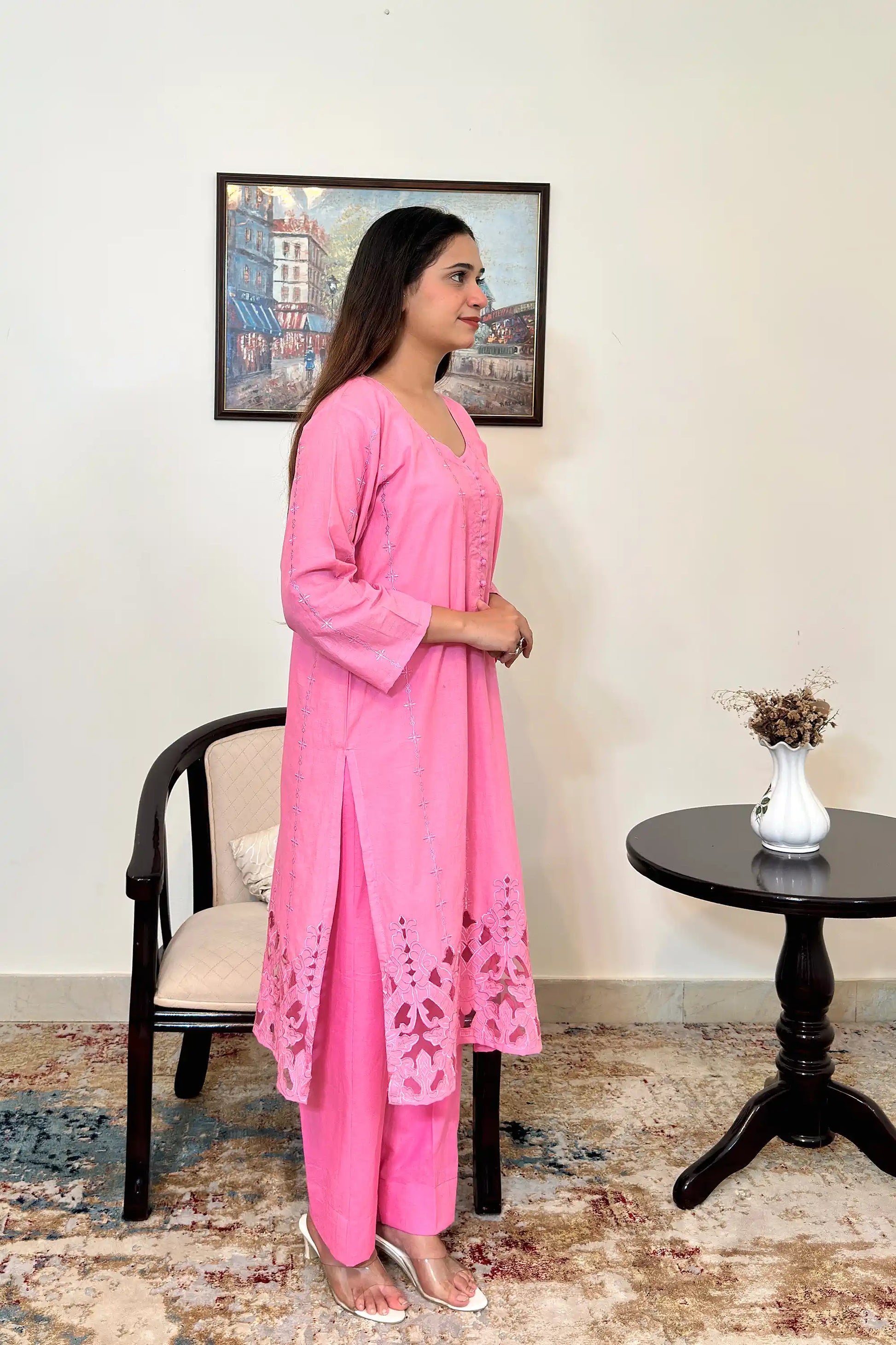 Right side view of the model wearing the pink cotton straight kurta and pink trousers, showing the side slit and the floral cutwork hem.