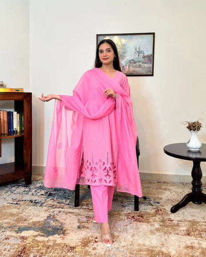 Model standing and holding the sheer pink supernet dupatta open with one arm extended, showing its scattered floral embroidery, with the kurta's floral cutwork hem visible.