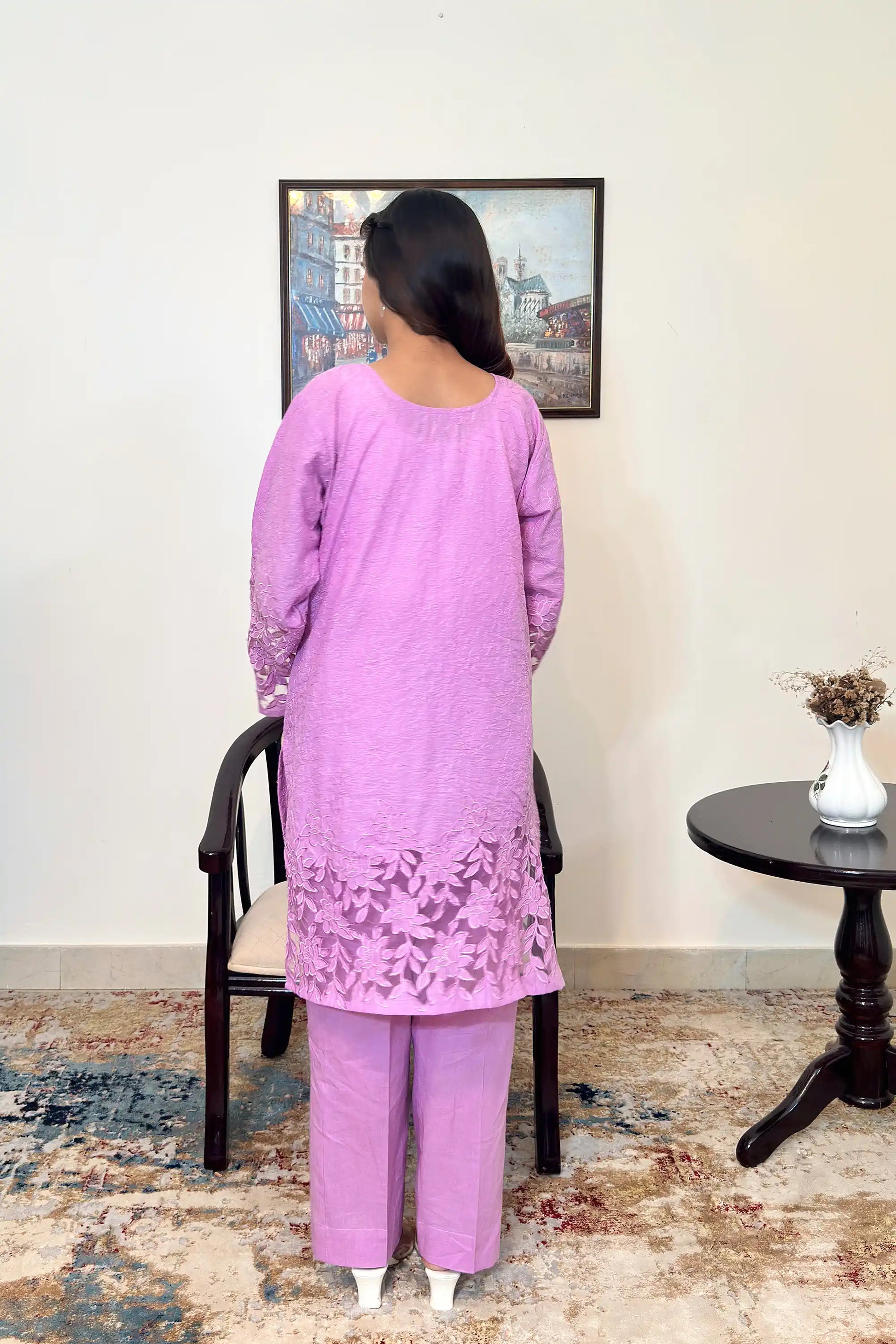 Back view of a purple cotton straight kurta worn with purple trousers, showing floral cutwork embroidery at the sleeves and hem.