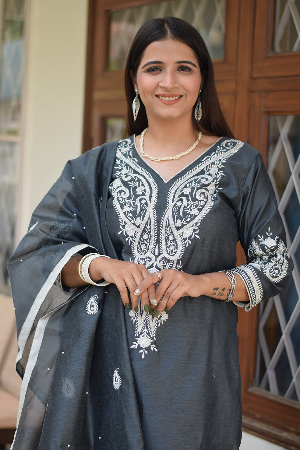 A woman wearing a grey kurta with a matching dupatta.